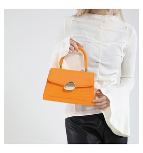 Détail du sac en cuir orange avec motif crocodile et boucle en métal doré