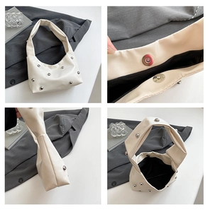 Detail view of beige studded hobo bag showing silver rivets, magnetic closure and interior