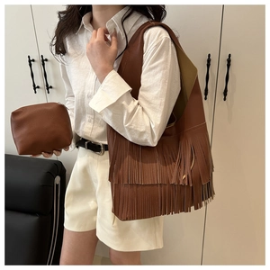 Detail of brown lychee pattern leather shoulder bag with decorative fringes and pouch