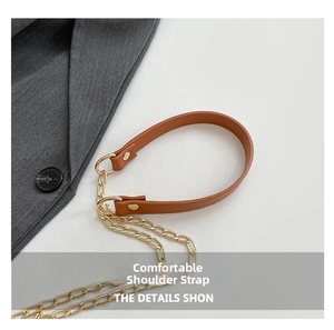 Detail of brown lychee leather shoulder strap with golden metal chain and rivets