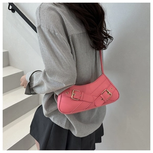 Detail of hot pink shoulder bag featuring gold hardware and biker-style strap accents