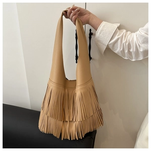 Detail of caramel hobo bag featuring long tassels and textured lychee leather grain