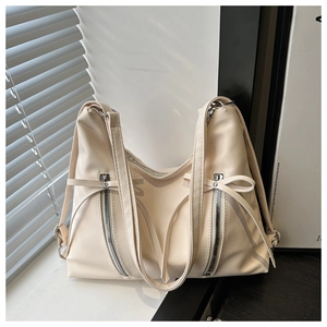 Détail du sac cabas en cuir crème avec des nœuds élégants et des fermetures éclair en métal