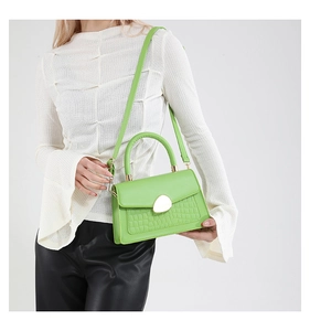 Détail du sac à main vert néon avec fermoir doré et texture en cuir motif crocodile