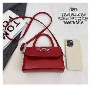 Macro view of red bow handbag showing glossy finish and size compared to a phone