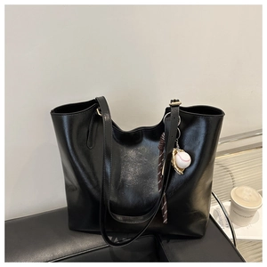 Detailed side view of black glossy tote bag featuring a baseball glove charm and large capacity
