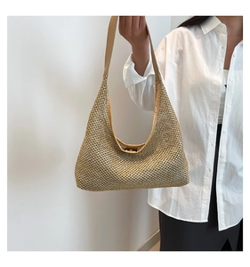 Detail of hand-woven hollow mesh texture on a golden summer straw shoulder bag