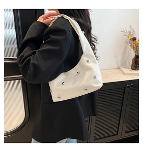 Detail of white glossy leather underarm bag featuring silver rivet sphere decorations
