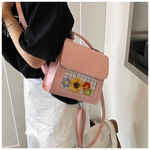 Dettaglio dello zaino in pelle rosa con ricamo di girasole nella finestra trasparente
