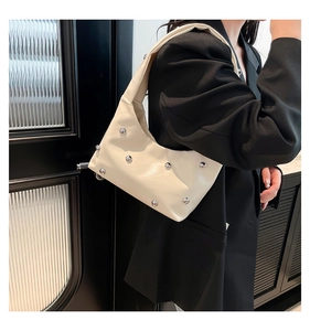 Detail of cream white half-moon bag featuring silver studs and wide shoulder strap