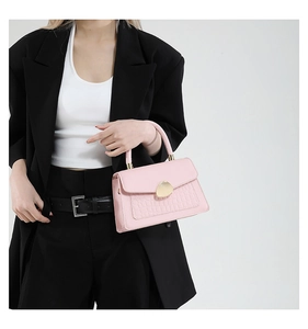 Gros plan d'un sac à main rose gaufré crocodile avec fermoir doré semi-circulaire