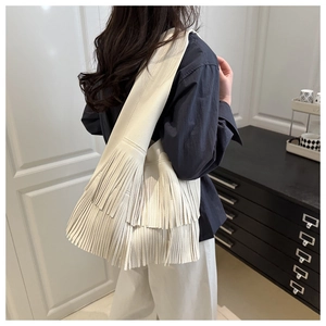 Detail view of white fringe tote bag with litchi grain texture and tassel design