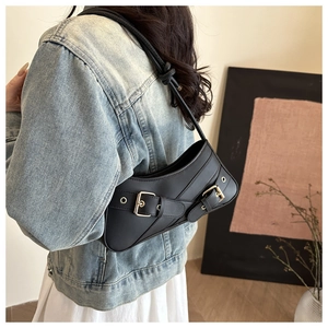 Detail of black faux leather underarm bag featuring dual metal buckle strap accents