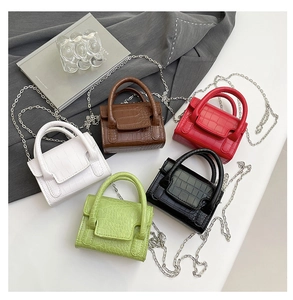 Flat lay of five stone pattern mini crossbody bags in white, brown, red, green, and black