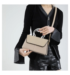 Detail of contrast handbag with metallic handle and woven flap worn by model