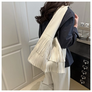 Detail shot of beige leather tassel tote bag with soft lychee texture and boho fringe