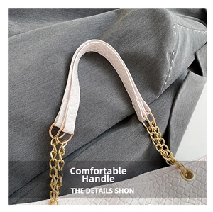 Detail of pink crocodile embossed handle with gold metal ring and chain link on tote bag