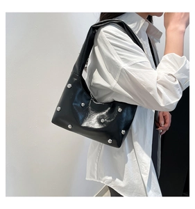 Detail of black glossy leather underarm bag with silver spherical rivets in retro punk style