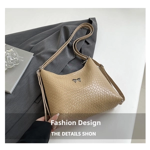 Detail of beige woven hobo bag featuring a silver metal bow pendant and fine leather texture