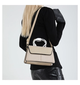 Detail of beige contrast handbag featuring woven flap and silver sculptural metal handle