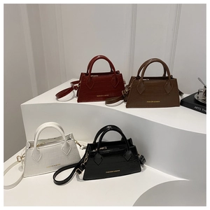 Detailed view of crocodile pattern leather handbags in red, brown, white and black