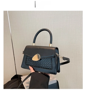 Détail du sac en cuir noir à texture crocodile avec fermoir métallique doré en forme de galet