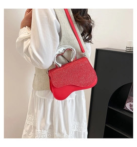 Detail view of red glitter handbag with wavy base and unique silver metal handle