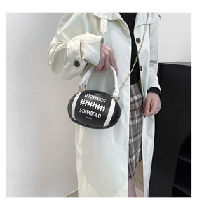 Close-up of a rugby-shaped crossbody bag with black and white panels and a gold chain