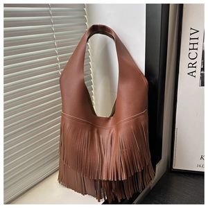 Dettaglio ravvicinato della pelle martellata marrone con lunghe nappe decorative sulla borsa