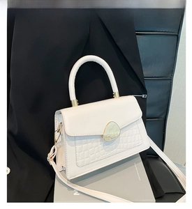 Détail du sac à main blanc motif crocodile avec fermoir doré et poignée structurée rigide