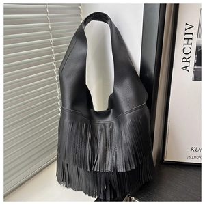 Dettaglio della borsa in pelle nera con lunghe frange e accenti di nappe per uno stile boho