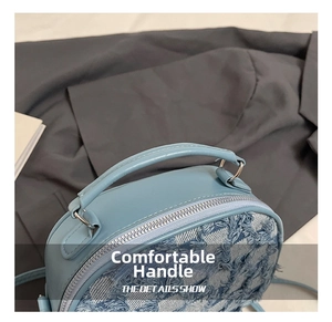 Detail der himmelblauen PU-Leder- und Denim-Handtasche mit gewölbtem Griff und Metallring