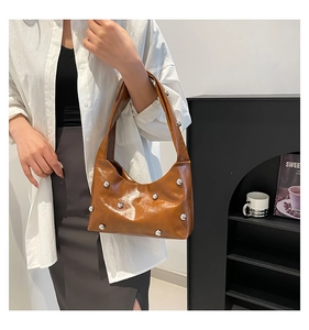 Close-up of brown patent leather underarm bag with silver spherical stud details