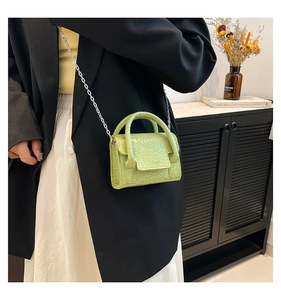 Detail of neon green mini bag with embossed crocodile texture and silver chain strap