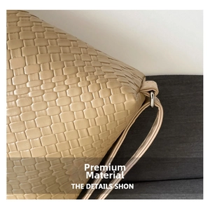 Close-up of woven leather texture on a beige tote bag with metallic ring detail