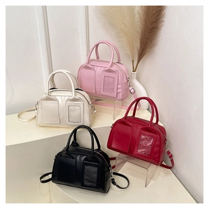 Gros plan de sacs Boston en cuir brillant stylés en rose, rouge, crème et noir