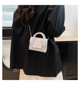 Close-up of white mini bag with crocodile texture and metal chain strap on model