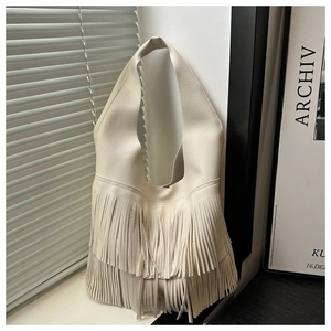 Dettaglio borsa hobo crema con texture in pelle martellata e frange eleganti