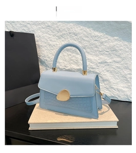 Détail du sac bleu clair à texture crocodile et boucle ovale dorée élégante