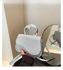 Detailed view of silver crossbody bag with sequined flap and arched metal handle