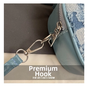 Detail des silbernen Metallhakens und D-Rings an blauer Denim-Tasche mit Krokostruktur
