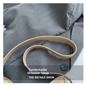 Détail de la bandoulière en cuir beige lisse avec bords polis sur un blazer gris chic