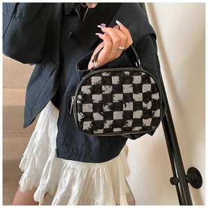 Détail d'un sac à main à carreaux avec franges en denim et fermeture éclair en métal