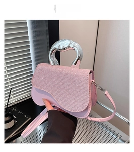 Close-up of pink saddle bag featuring sparkling rhinestone surface and silver art handle