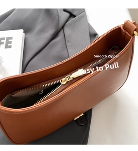 Close-up of golden zipper detail on caramel leather shoulder bag with dark gray lining