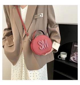 Detail of red circular crossbody bag with 3D SM embossing and fine stitching