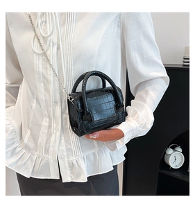 Macro detail of black crocodile pattern mini handbag with silver chain and top handle