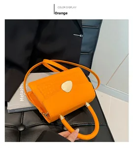 Détail du sac orange en similicuir avec boucle cœur posé sur une chaise en cuir noir