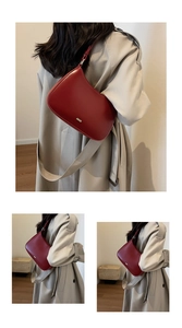 Detail of a dark red leather hobo bag with a gold metal logo and adjustable strap