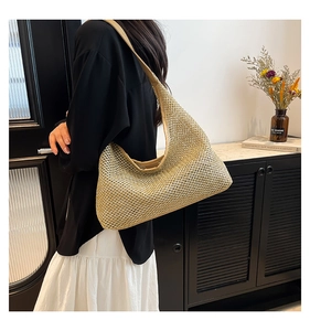 Detail of woven straw shoulder bag featuring tan leather trim and intricate mesh pattern